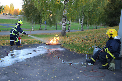 Juliet Järvensivu sammuttaa paloa nestesammuttimella, ja harjoitusta valvoo Niko Koivumäki.
