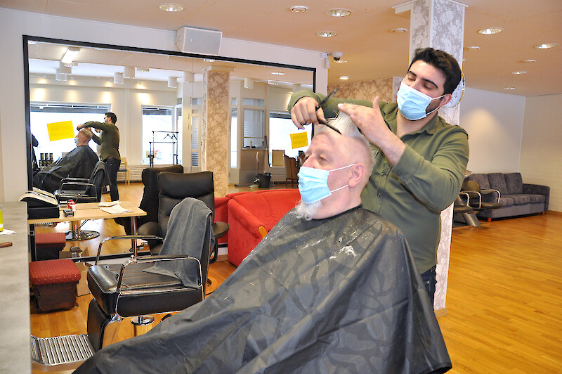 Turkkilainen Ekrem Özonur leikkaa miesten hiuksia ja partoja Ikaalisissa. Parturintuolissa asiakkaana on ikaalilainen Harri Kiuru.
