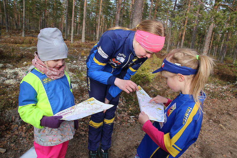 Helmi Latvajärvi ja Iita Vitikainen tutkivat karttoja ennen suunnistusharjoitukseen lähtöä. Neuvoja antaa heitä ohjaava Elsa Myllymäki (keskellä).