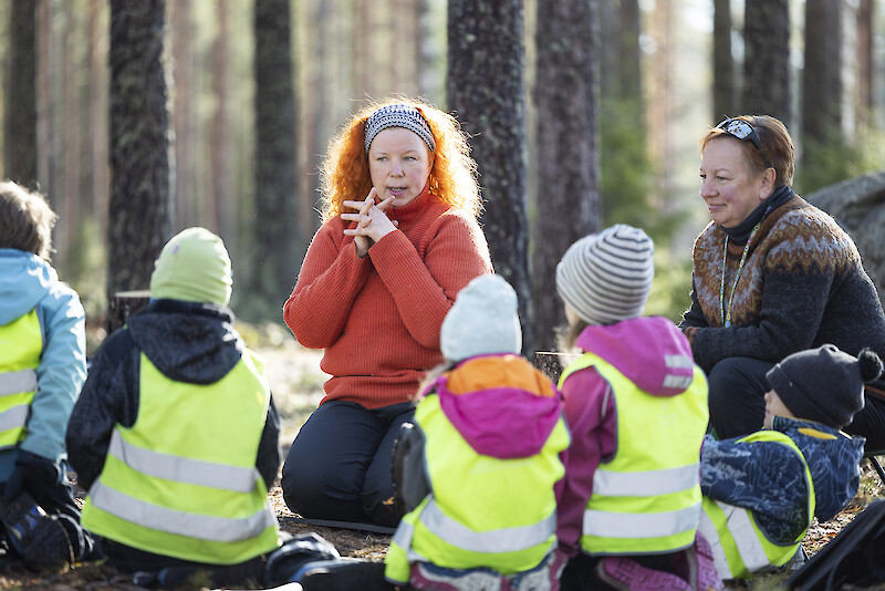 Varhaiskasvatuksen opettaja Ulla Rutanen ja lastenhoitaja Lissu Bamberg vetävät opetustuokiota eskareiden ja vähän pienempien metsäryhmälle.