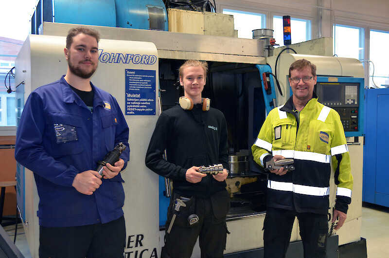 Henri Ruponen, Jan Alatare ja Esko Koskiniemi Saskysta näyttävät AGCO Powerin lahjoittaman työstökeskuksen edessä esimerkkejä siitä mitä AGCO Powerilta saadusta lahjoitustavarasta voi koneistaa.