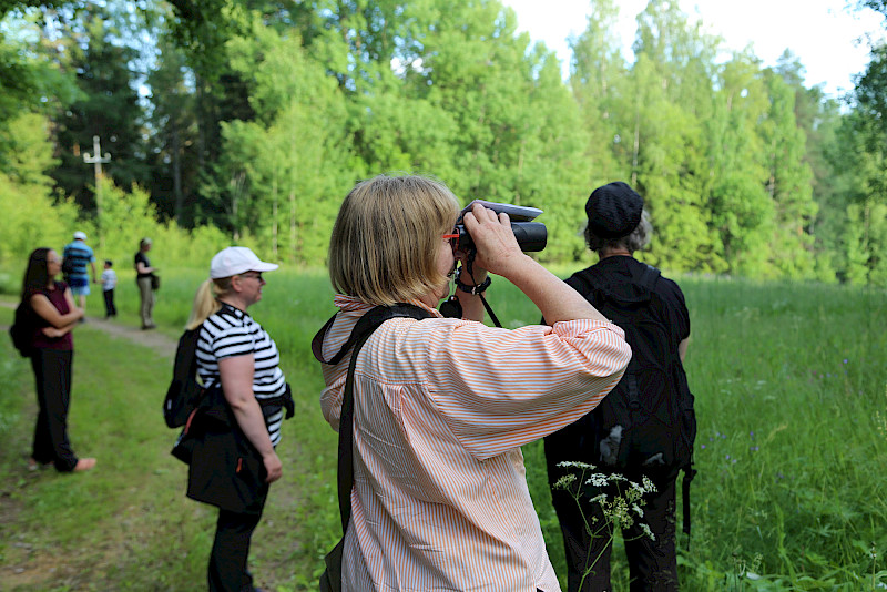 Kovelahden iltakävelyllä katseltiin ja kuunneltiin luontoa. Kävelijöille kasveista ja linnuista kertoili muun muassa kuvassa kiikaroiva biologi Eira-Maija Savonen.